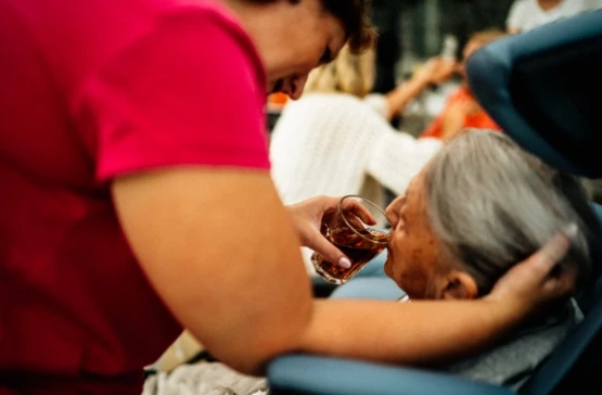 A caring woman gently feeds an elderly woman with a spoon, showcasing a moment of compassion and connection between them.