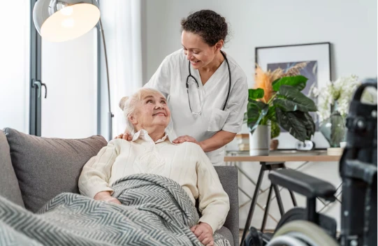 A woman in a wheelchair sits beside a private caregiver, both engaged in a warm conversation, showcasing companionship and support.